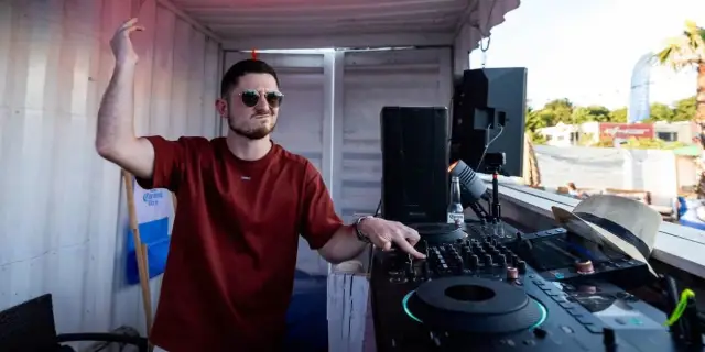 ASTR behind the decks with one arm raised