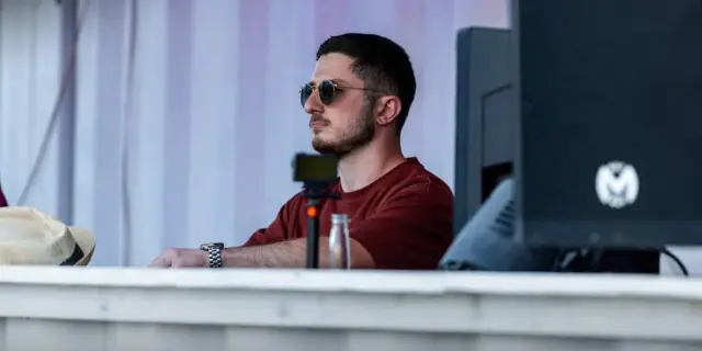 ASTR wearing sunglasses behind the booth
